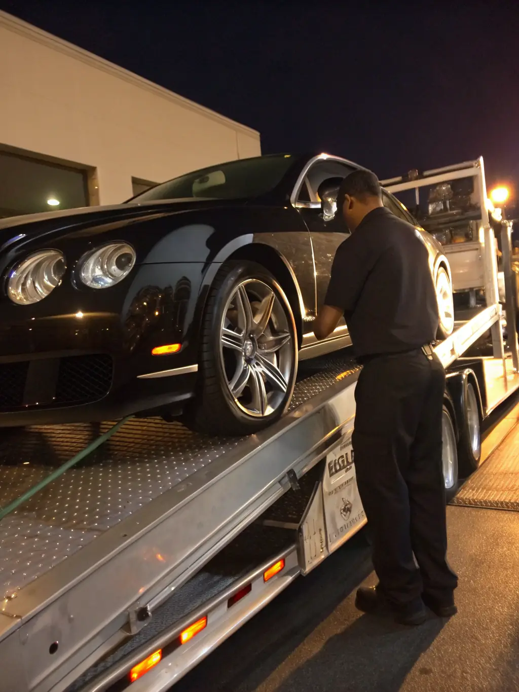 A photograph of a luxury car being carefully loaded onto a transport truck, ready for final delivery to the client.